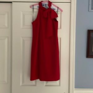 Red halter evening sheath . Hits above the knee. Bow on left shoulder.